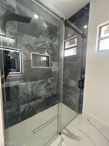 Bathroom featuring a marble finish shower and marble look tiles