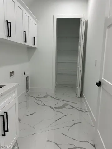 Laundry room featuring cabinet space, hookup for a washing machine, light marble finish flooring, and electric dryer hookup