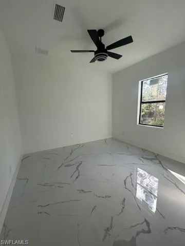 Spare room featuring light marble finish flooring and ceiling fan
