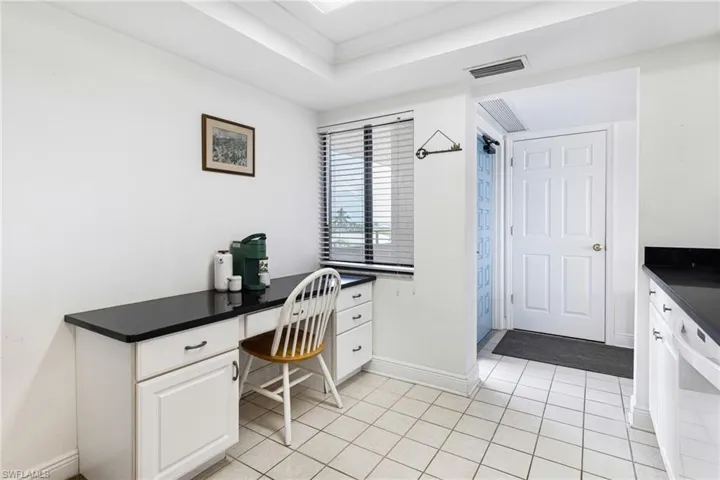 Office space with ornamental molding, light tile patterned floors, and a raised ceiling