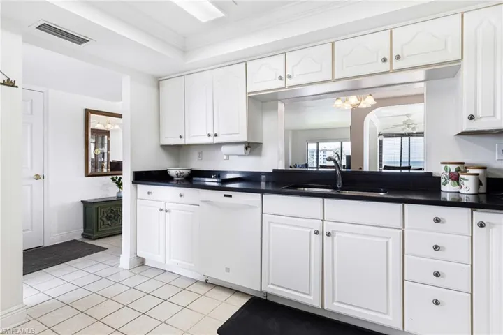 Kitchen with white cabinets, sink, dishwasher, and crown molding