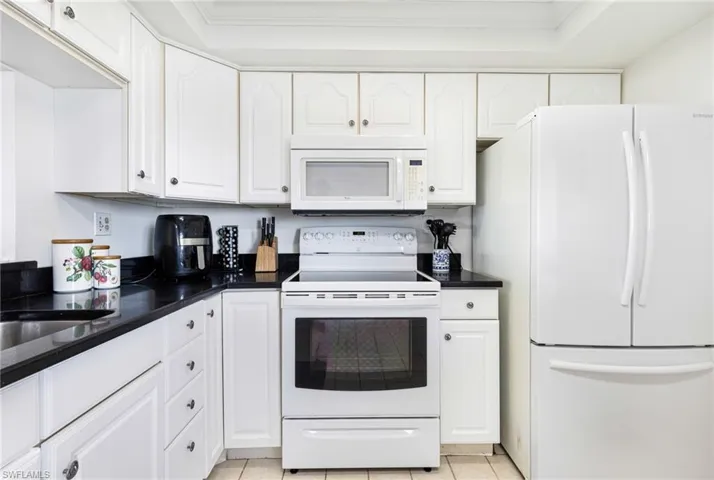 Kitchen featuring white cabinets, white appliances, and crown molding