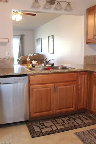 Kitchen featuring open floor plan, a peninsula, dishwasher, ceiling fan, and light tile patterned floors