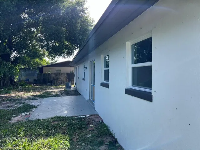 View of side of property with a patio area, stucco siding, and central air condition unit