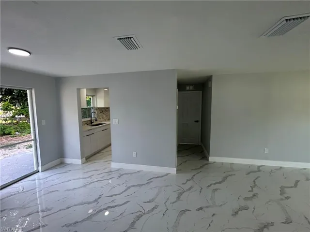 Empty room featuring a sink, baseboards, and light marble finish flooring