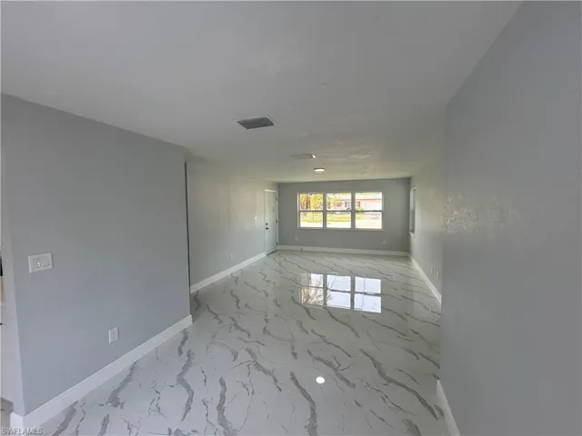 Spare room featuring marble finish floors and baseboards