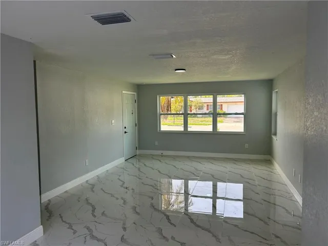 Unfurnished room with marble look tiles and baseboards