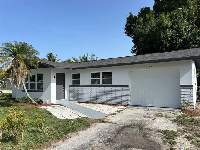 Ranch-style home with stucco siding, a garage, driveway, and a shingled roof