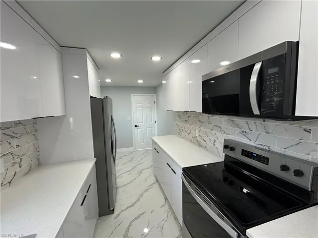 Kitchen with appliances with stainless steel finishes, modern cabinets, white cabinets, recessed lighting, and decorative backsplash