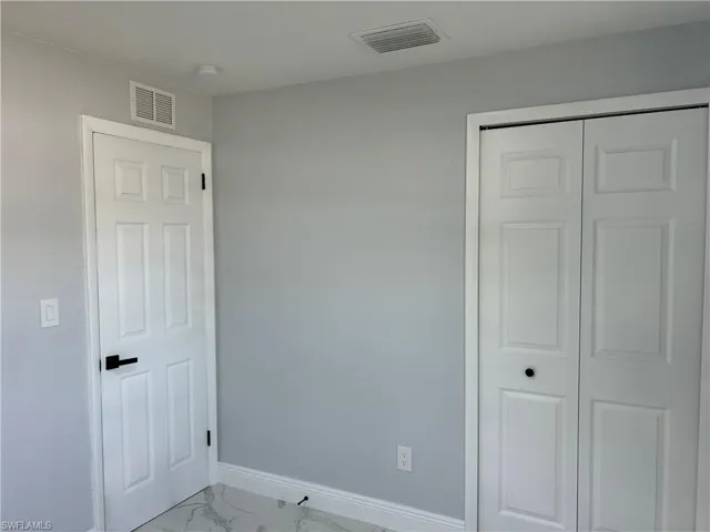 Unfurnished bedroom with marble finish flooring, baseboards, and a closet