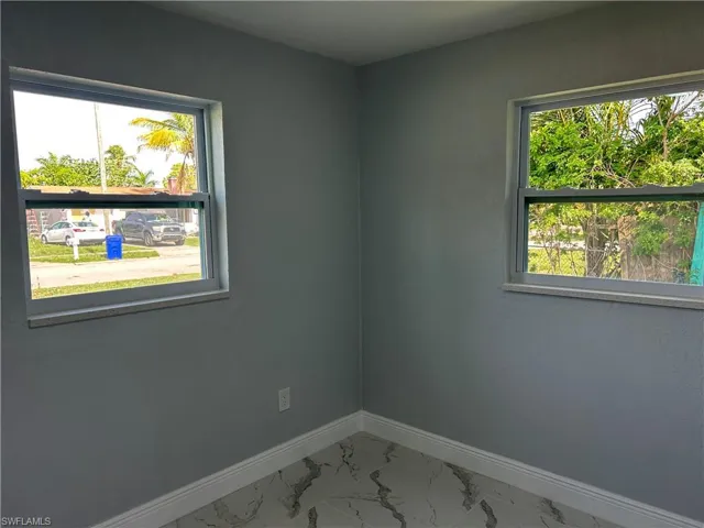 Unfurnished room with healthy amount of natural light, baseboards, and marble look tile flooring