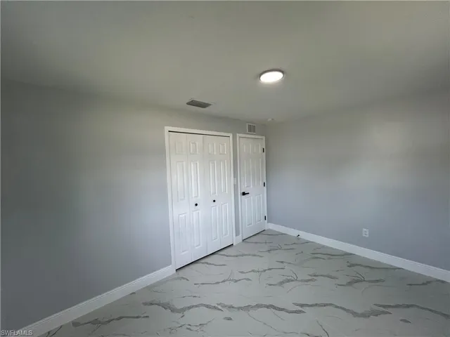 Unfurnished bedroom with marble look tile flooring, baseboards, and a closet