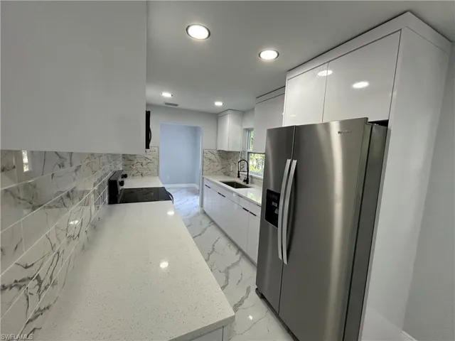 Kitchen with stainless steel refrigerator with ice dispenser, modern cabinets, stove, a sink, and recessed lighting