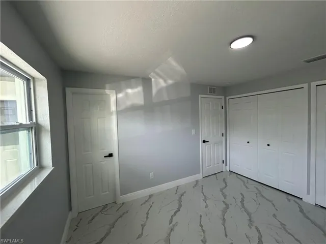 Unfurnished bedroom featuring baseboards and light marble finish floors