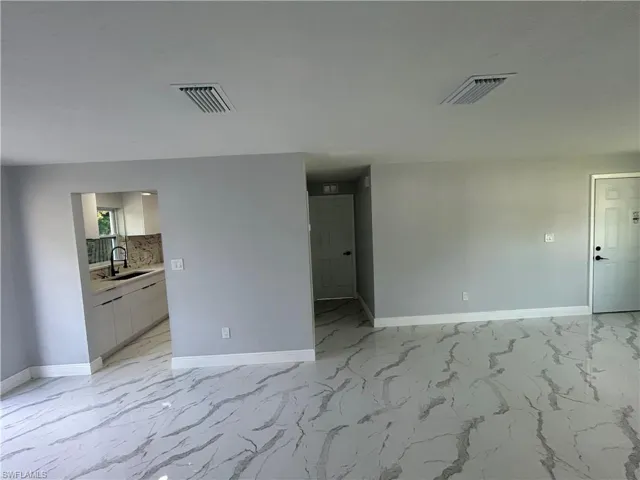 Empty room with baseboards, a sink, and light marble finish flooring