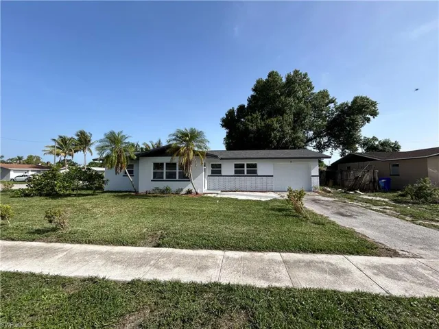 Single story home featuring a garage, concrete driveway, a front yard, and stucco siding