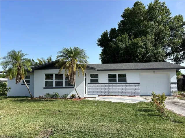 Ranch-style home with stucco siding, a garage, concrete driveway, and a front lawn