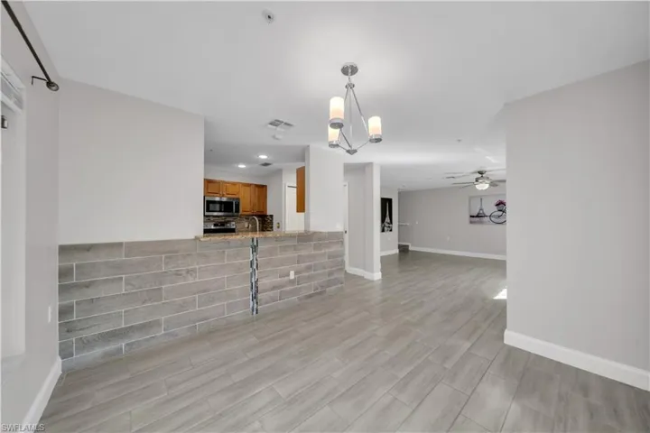 Unfurnished living room with a chandelier, a ceiling fan, light wood-style flooring, and recessed lighting