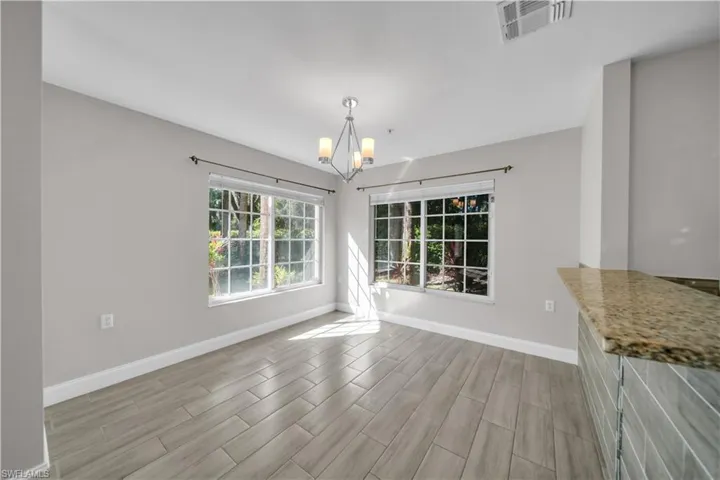 Unfurnished dining area with wood finish floors and a chandelier