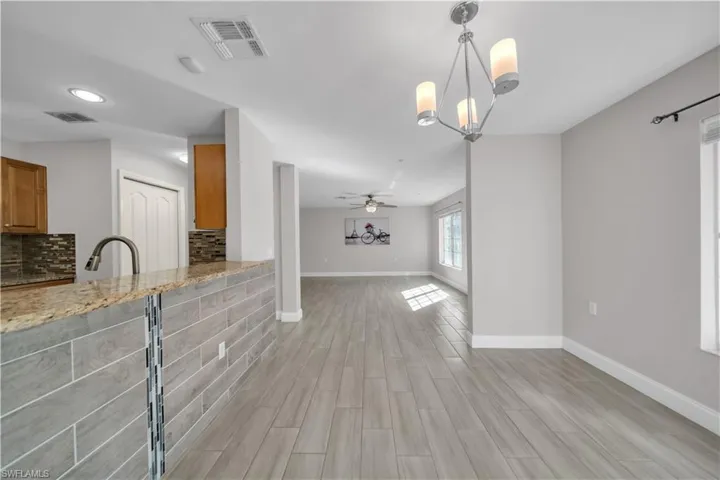 Unfurnished living room with a chandelier, ceiling fan, wood tiled floors, and recessed lighting