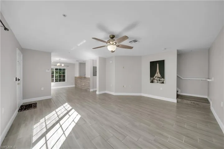 Unfurnished living room featuring wood finish floors, ceiling fan, and a chandelier
