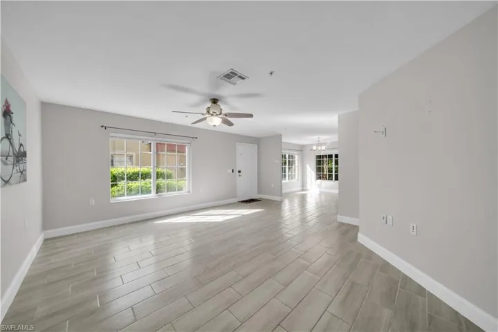 Unfurnished living room with plenty of natural light, wood finish floors, a chandelier, and ceiling fan