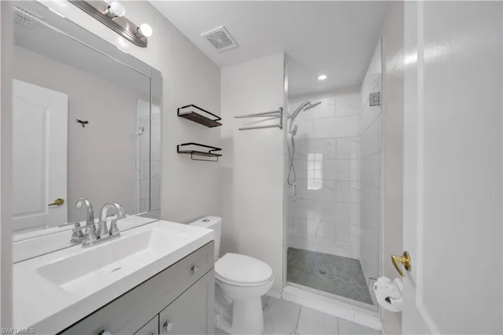 Full bathroom with vanity, a shower stall, recessed lighting, and light marble finish flooring