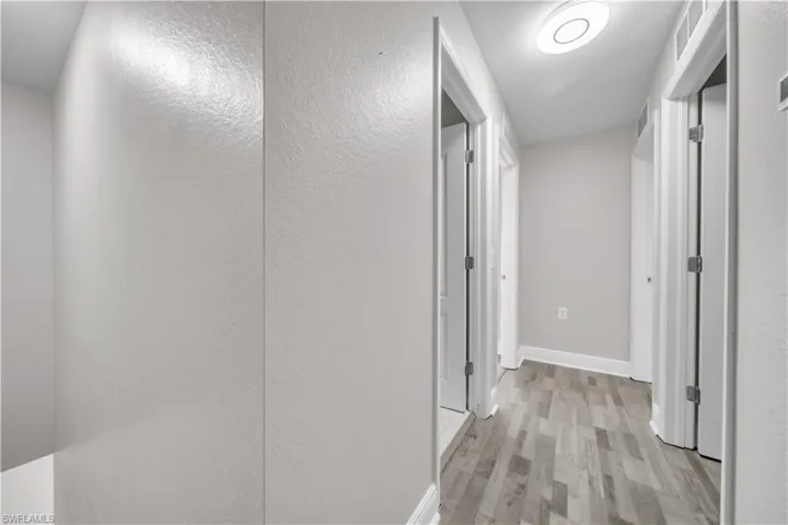 Hall featuring light wood-type flooring and a textured wall