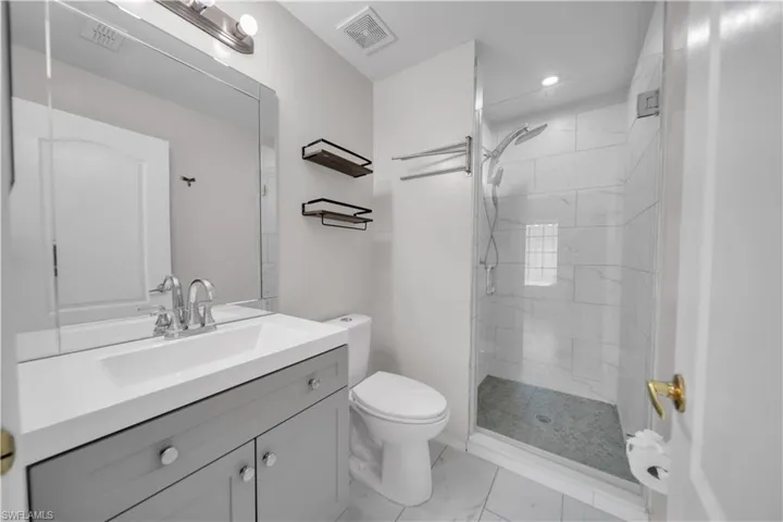 Bathroom with vanity, a stall shower, light marble finish floors, and recessed lighting