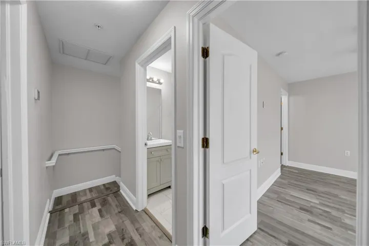 Corridor featuring light wood finished floors and attic access