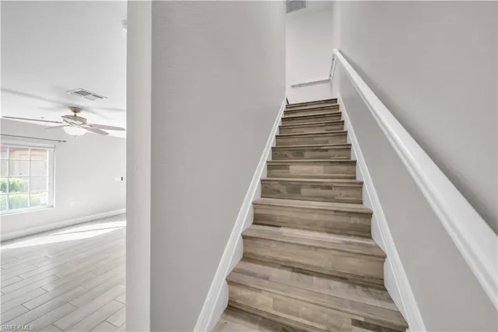 Stairs with wood finished floors and ceiling fan