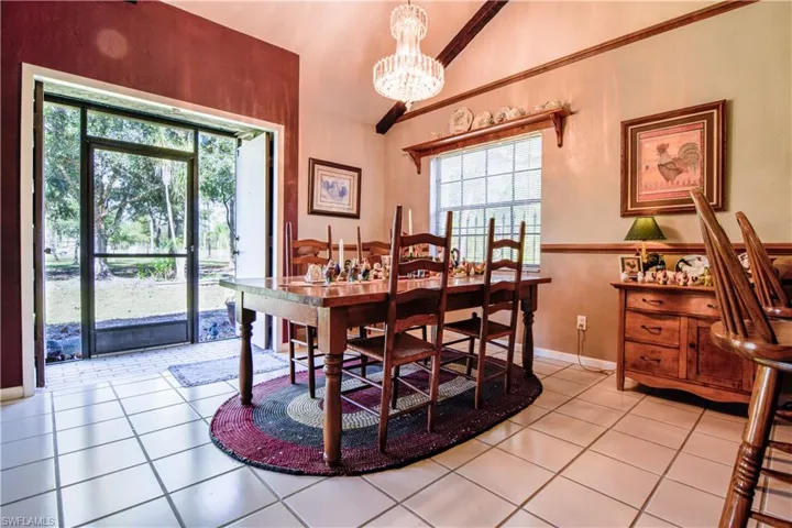 Dining Area Of The Great Room With Views Of The Lake And Circular Driveway. Featuring A Glass Chandelier, Soaring Ceilings And A Breakfast Bar Into The Kitchen.