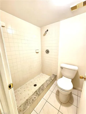 Walk-in shower with a marble-finish bench and tiled walls