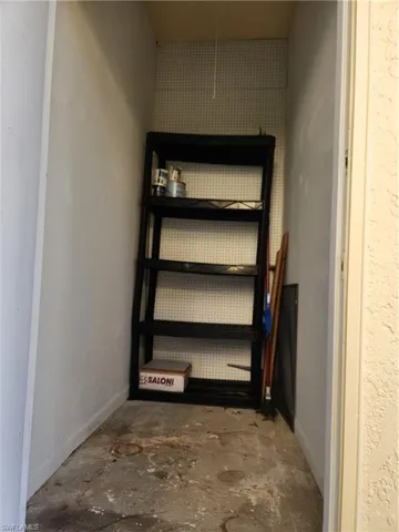 Enclosed storage area featuring concrete flooring and white pegboard wall panels