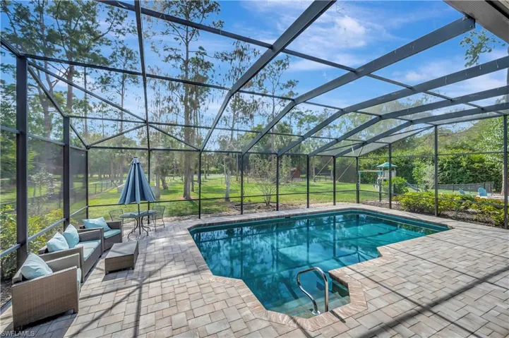 View of pool with an outdoor hangout area, a lawn, glass enclosure, and a patio area