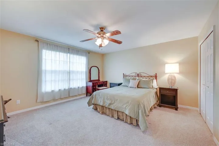 Bedroom with ceiling fan, light carpet, and a closet