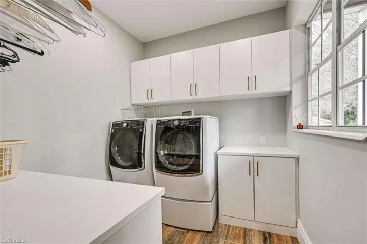 Washroom with light wood-type flooring, independent washer and dryer, and cabinets