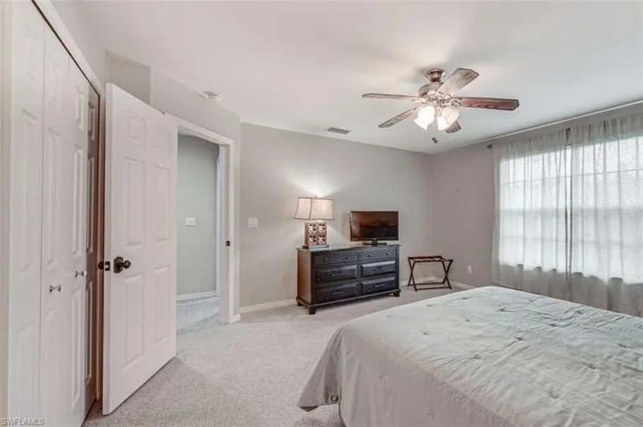 Bedroom with light colored carpet, a closet, and ceiling fan