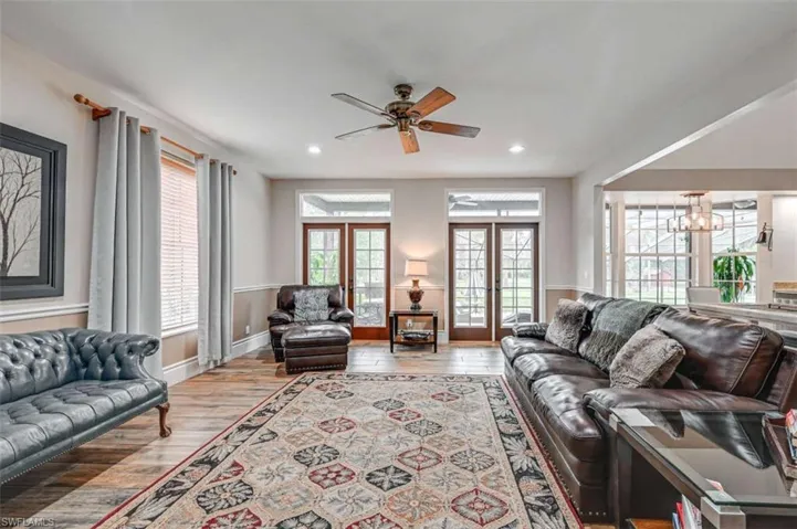 Living room featuring french doors, ceiling fan with notable chandelier, plenty of natural light, and light hardwood / wood-style floors
