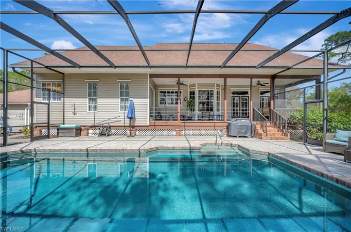 View of pool with ceiling fan, glass enclosure, a grill, and a patio area