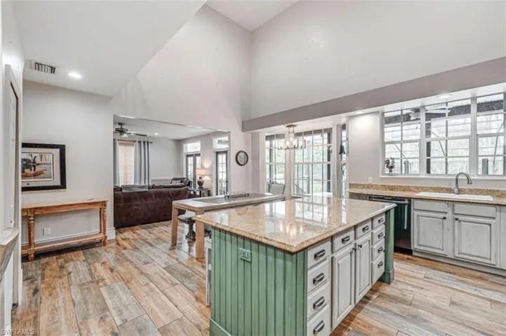 Kitchen with sink, ceiling fan with notable chandelier, a center island, and light hardwood / wood-style floors