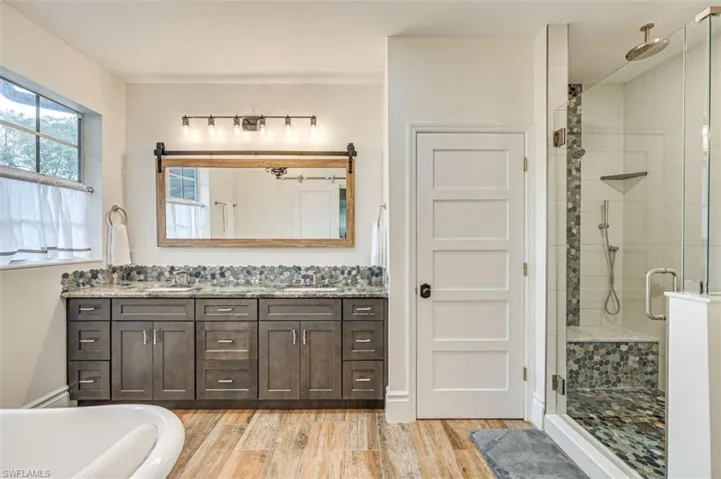Bathroom with double vanity, hardwood / wood-style flooring, and independent shower and bath