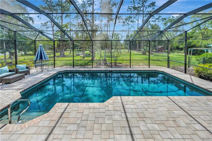 View of swimming pool featuring glass enclosure, a patio area, and a yard