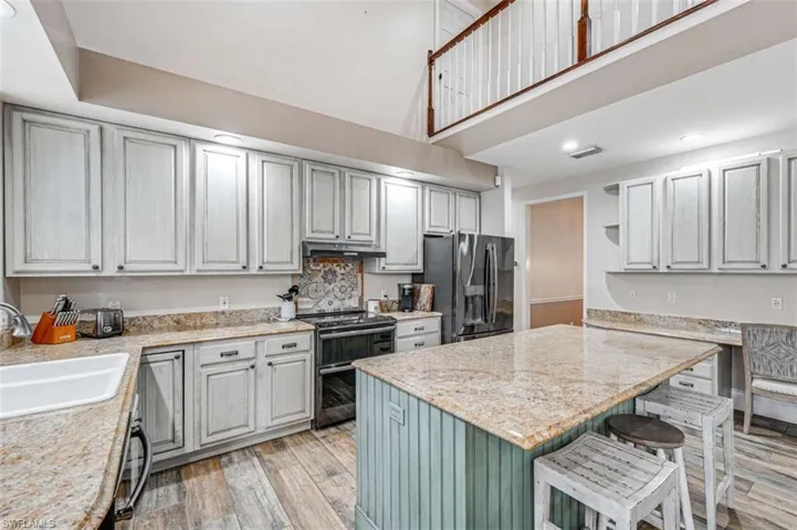 Kitchen featuring a breakfast bar area, stainless steel appliances, light hardwood / wood-style floors, light stone counters, and sink