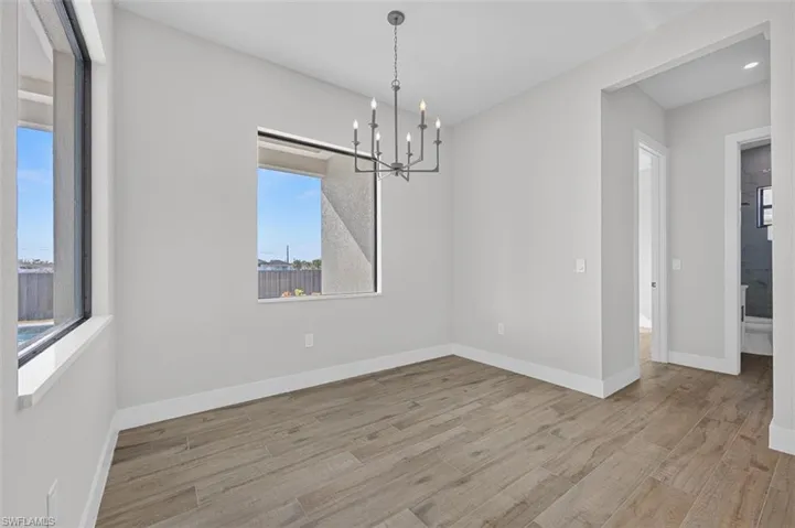 Spare room with a chandelier and wood finished floors
