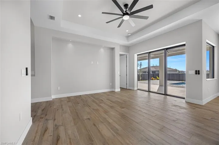 Empty room featuring a ceiling fan, a raised ceiling, wood finished floors, and recessed lighting