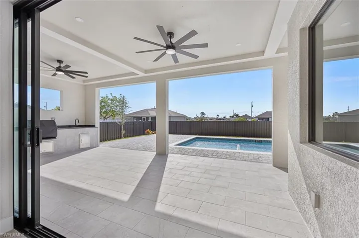 View of pool featuring a ceiling fan, an outdoor kitchen, a patio area, and a fenced backyard