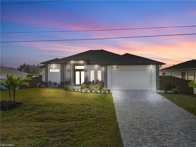 View of front of home with a garage, stucco siding, decorative driveway, and roof with shingles