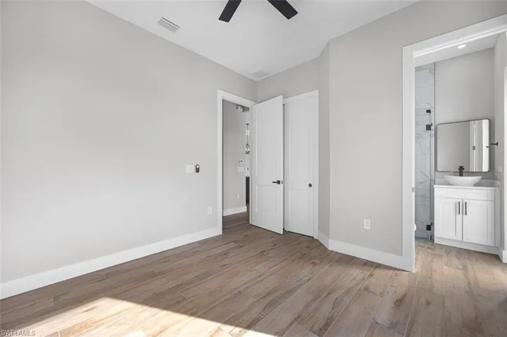 Unfurnished bedroom with light wood finished floors, a closet, connected bathroom, and ceiling fan