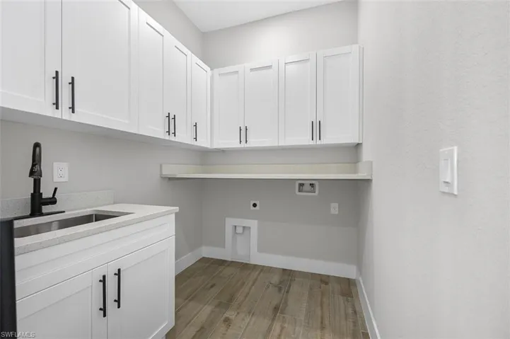 Laundry room with electric dryer hookup, washer hookup, wood finished floors, and cabinet space